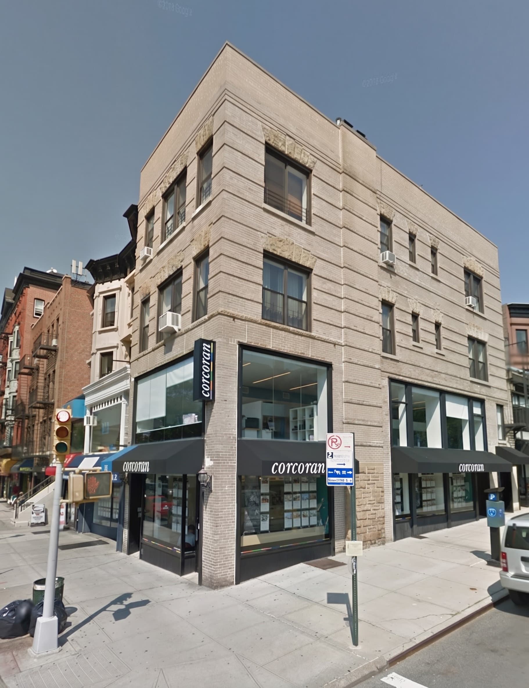 Corner mixed-use tan-brick building with a ground-floor commercial storefront