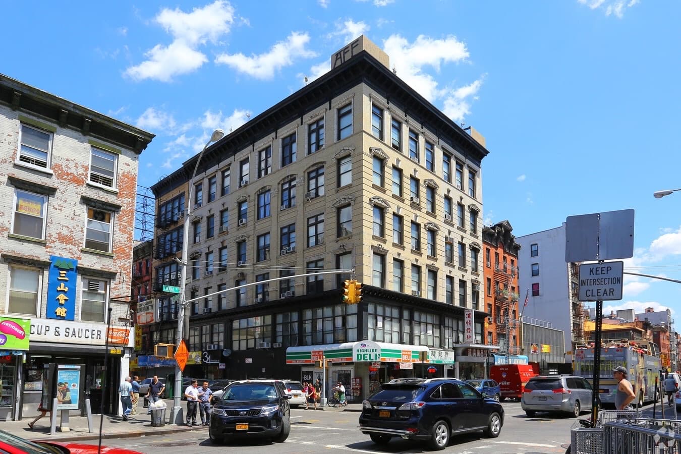 Corner mixed-use brick building on a busy Manhattan street